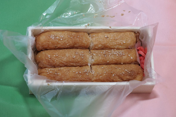 光泉のいなり寿司(持ち帰り)650円。いなり6個、紅生姜に箸がついています。店内で食べることもできます。店内にはテーブル席が10席ほどと、小上がり(座卓ひとつ)があります。